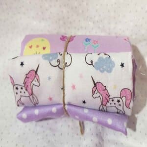 Restos de telas con motivos  infantiles en rosas y lilas(Aproximadamente 50 cm)